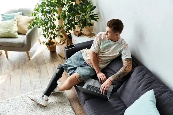 Handsome young man engages with his laptop, showing determination while seated comfortably. — Stock Photo