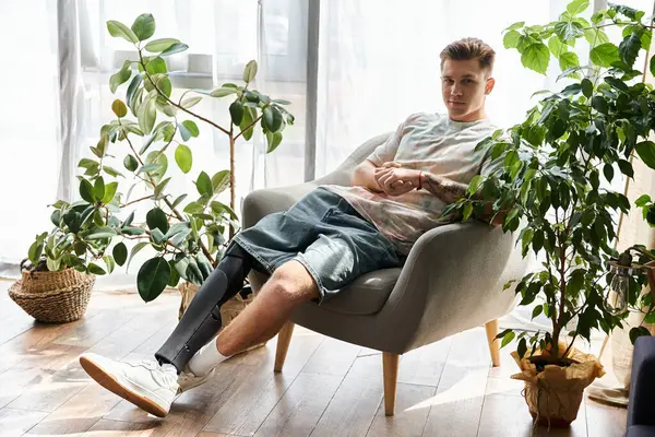 A young man relaxes in an armchair, showcasing his prosthetic leg in a calm setting. — Stock Photo