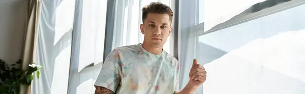 A young handsome man strikes a confident pose in a bright room. — Stock Photo