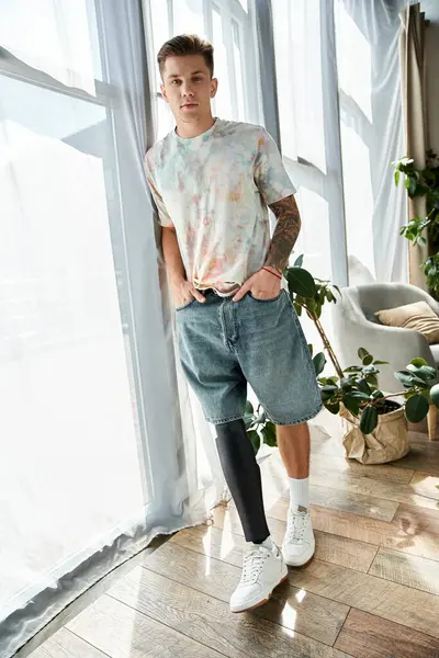 Young man with prosthetic leg stands proudly in a bright, modern apartment, showing his style. — Stock Photo