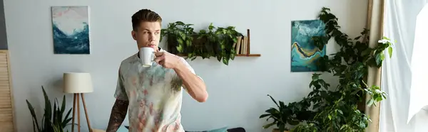 Handsome young man sips coffee in a bright and inviting home environment. — Stock Photo