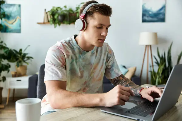 Concentrated young man working on a laptop in a bright, stylish room. — Stock Photo