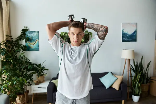 Showing resilience, a young man lifts weights at home, inspiring strength and focus in his workout. — Stock Photo