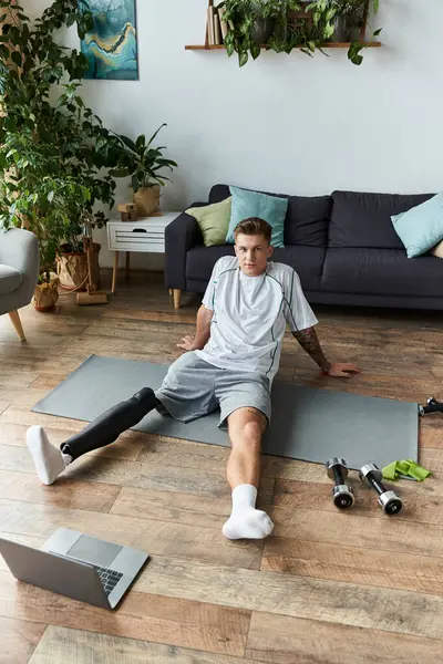 Um jovem bonito relaxa em um tapete após um treino intenso, mostrando sua perna protética. — Fotografia de Stock