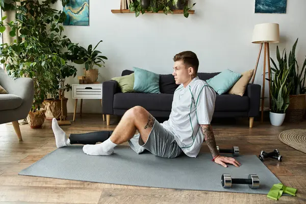 Young man trains at home, demonstrating strength with a prosthetic leg. — Stock Photo