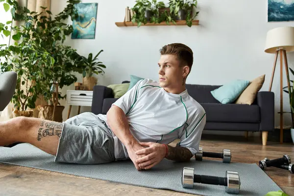 A handsome young man exercises on a mat in his well decorated living area, showing determination. — Stock Photo
