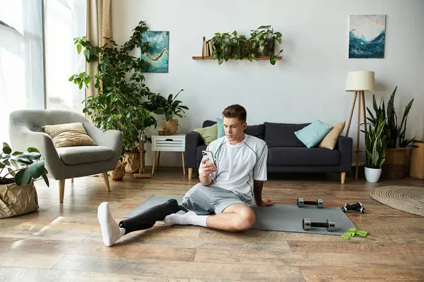 Handsome young man sitting on the floor while checking his phone in a stylish living room space. — Stock Photo