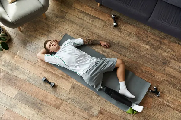 Young man rests on yoga mat, showcasing determination and strength with prosthetic leg. — Stock Photo