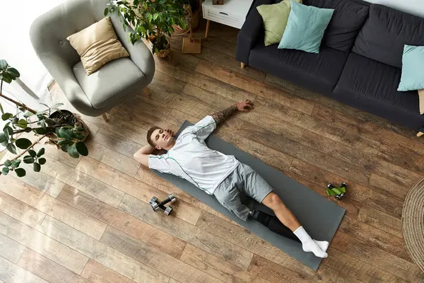 Relaxed young man with prosthetic leg enjoys a moment of rest on exercise mat in stylish space. — Stock Photo