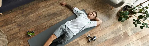 Handsome young man with a prosthetic leg stretches on a mat after an intense workout session. — Stock Photo