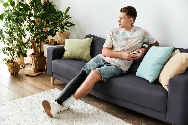 Questo giovane, bell'uomo si siede comodamente su un divano, godendo di un momento di relax a casa. — Foto stock