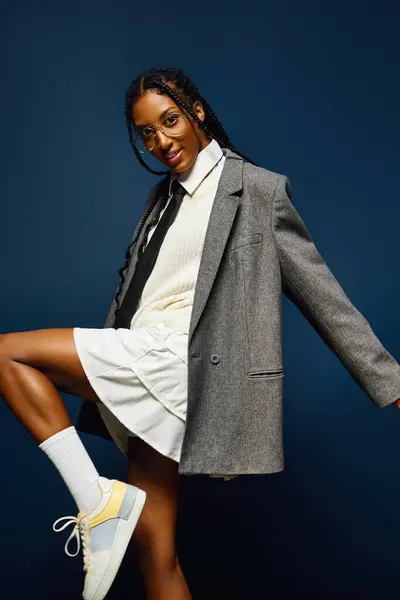 Une jeune femme confiante pose dans un blazer chic surdimensionné sur fond bleu profond. — Photo de stock