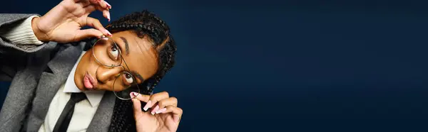 Bright eyed young woman with braided hair is playfully adjusting her glasses with a smile. — Stock Photo