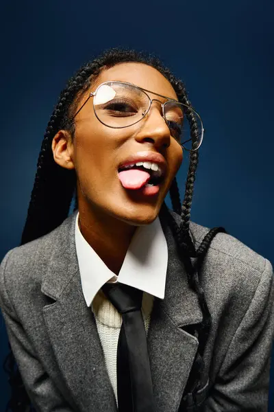 A vibrant young woman showcases her playful personality while wearing glasses and a stylish suit. — Stock Photo
