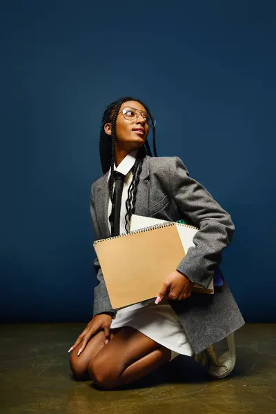 A young woman kneels with a notebook, displaying her unique style and confidence. — Stock Photo