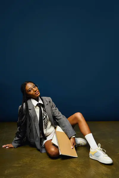 A young woman lounges on the floor, flaunting her stylish outfit and confidence. — Stock Photo