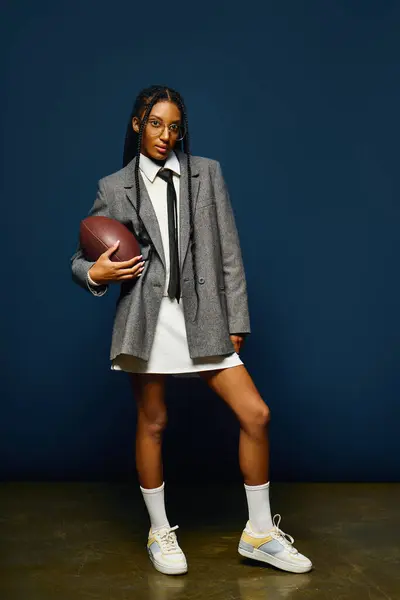 Stylish young woman stands confidently with a football, embodying a blend of sport and fashion. — Stock Photo