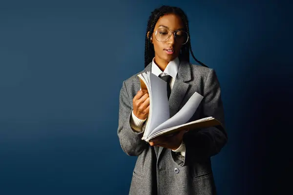 Focused young woman flipping through her notes while dressed in a chic oversized outfit — Stock Photo