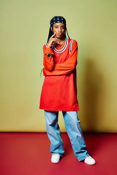 A stylish young woman stands with poise in a bright red outfit, showcasing her unique fashion sense. — Stock Photo