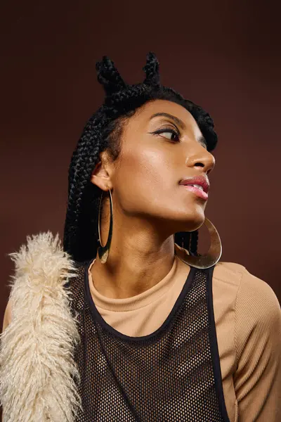 Beautiful young woman showcases unique style with braided hair and striking jewelry while posing. — Stock Photo
