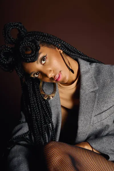 A beautiful young woman with intricate braids poses gracefully while dressed in modern attire. — Stock Photo