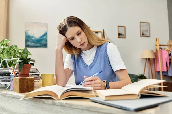 Une adolescente concentrée étudie avec diligence à son bureau, entourée de confort à la maison. — Photo de stock