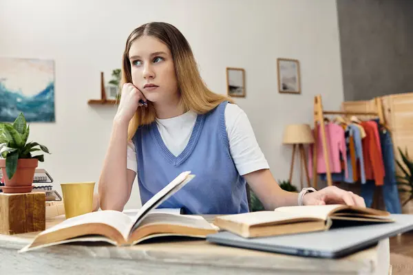 A teenage girl sits thoughtfully at her desk, immersed in books and her personal space. — Stock Photo
