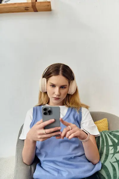 Uma adolescente relaxa em seu quarto acolhedor, focada em seu smartphone enquanto usa fones de ouvido. — Fotografia de Stock