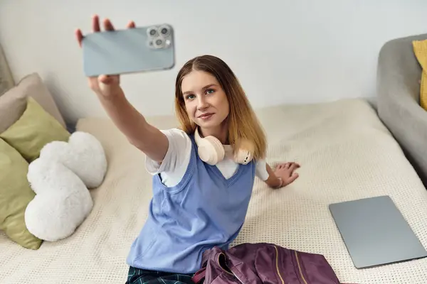 A teenage girl takes a selfie on her bed, highlighting youth culture in her stylish room. — Stock Photo
