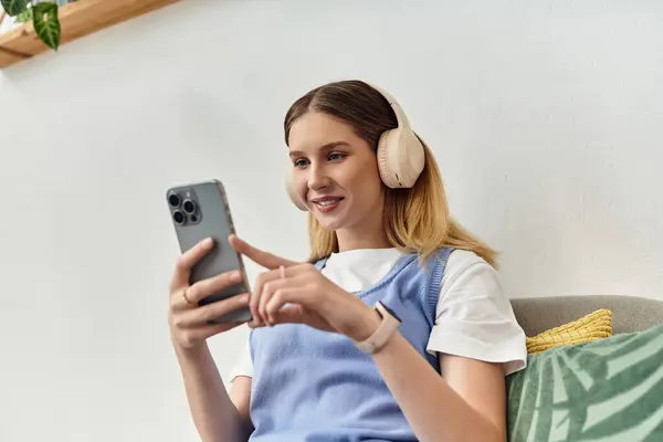 Uma adolescente moderna desfruta de seu tempo livre explorando música em seu smartphone em seu quarto. — Fotografia de Stock