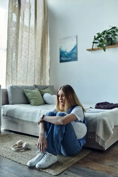 A teenage girl sits comfortably on the floor, reflecting in her stylish room filled with decor. — Foto stock