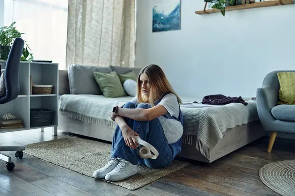 Teenage girl sits on the floor of her room, lost in thought, surrounded by her favorite things. — Stock Photo