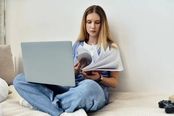A teenage girl sits cross-legged, surrounded by books and a laptop, immersed in her studies at home. — Stock Photo