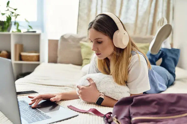 Uma adolescente relaxa em seu quarto, envolvida com seu laptop enquanto usa fones de ouvido. — Fotografia de Stock