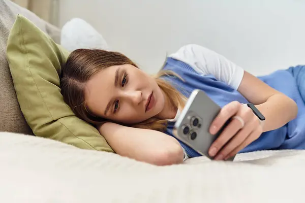 Uma adolescente relaxa em sua cama, absorvida em seu smartphone enquanto desfruta de seu espaço. — Fotografia de Stock