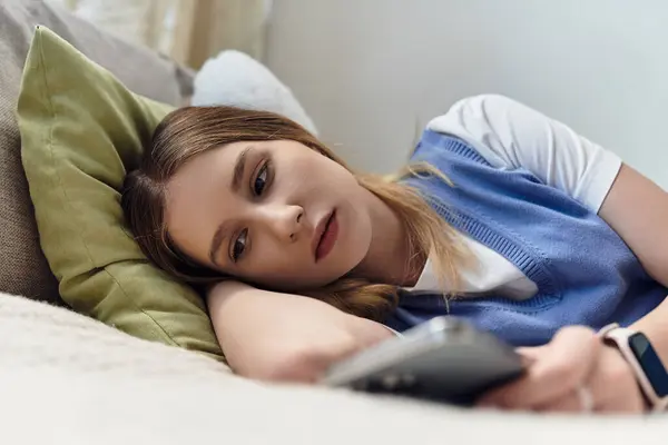 A teenage girl lounges in her room, engaging with her smartphone in a relaxed moment. — Stock Photo