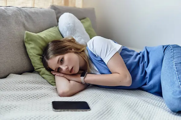 Young girl relaxes on her bed with her phone nearby, lost in thought about her day. — Stock Photo