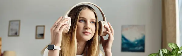 A pretty teenage girl listens to music with headphones in her stylish room, embracing youth culture, banner — Stock Photo