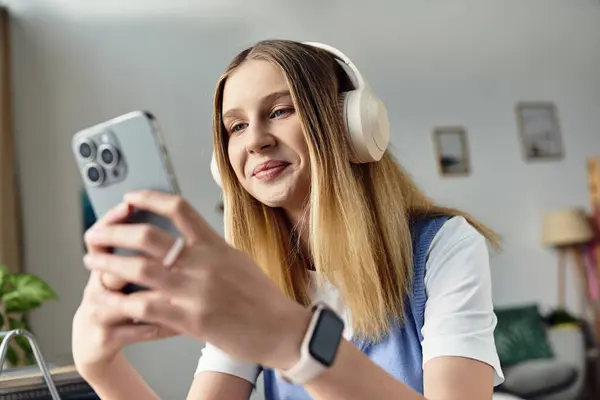 A teenage girl relaxes in her room, using her smartphone and listening to music with headphones. — Stock Photo