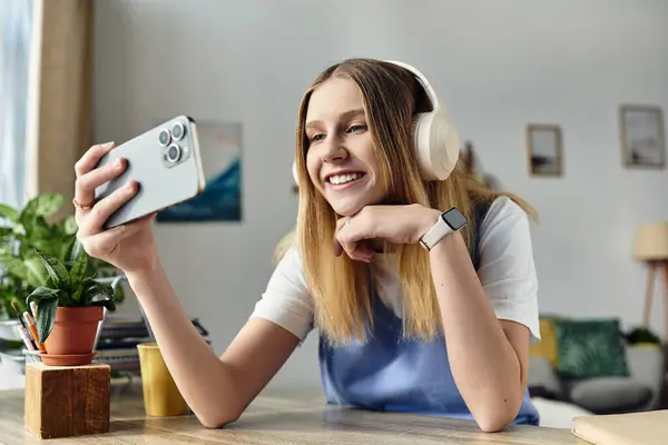A cheerful girl relaxes in her stylish room, enjoying time on her smartphone. — Stock Photo
