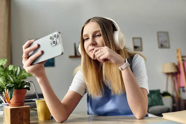 Un'adolescente si rilassa nella sua accogliente stanza, interagendo con il suo smartphone mentre indossa le cuffie. — Foto stock