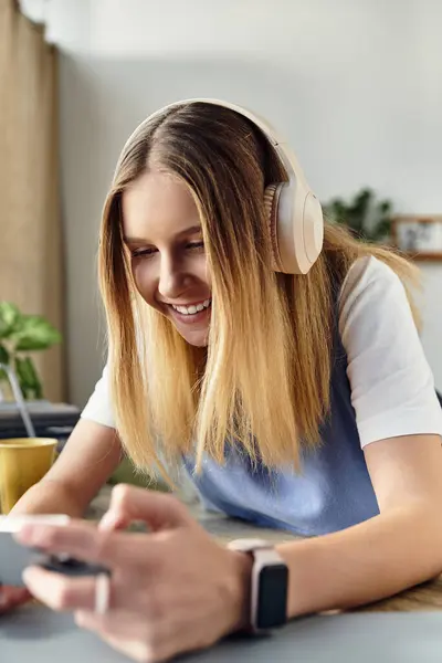 A teenage girl is immersed in her smartphone while listening to music. She exudes joy in her room. — Stock Photo
