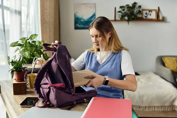 A pretty teenage girl organizes her schoolwork at home, surrounded by her personal space and plants. — Stock Photo