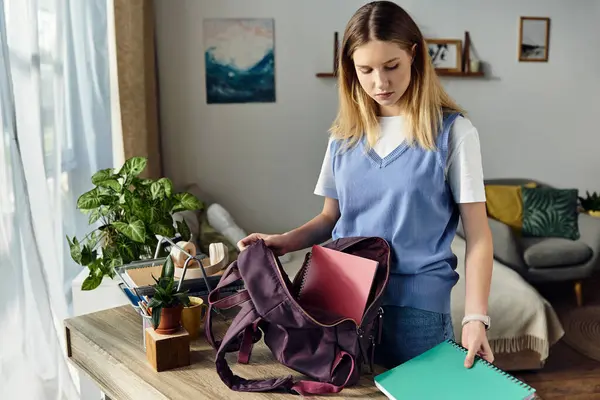 A teenage girl organizes her notebooks and backpack in her chic living space, celebrating youth. — Stock Photo