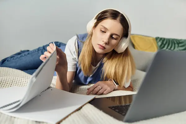 Godendo del suo tempo libero, una ragazza ascolta musica mentre lavora a un progetto a casa. — Foto stock