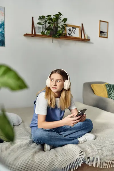 Teenage girl with headphones sits comfortably while browsing her phone, embracing her space. — Stock Photo