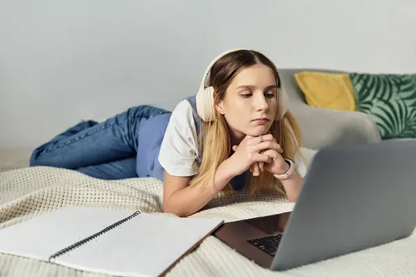 A pretty teenage girl in casual attire is engaged with her laptop in a modern, stylish room. — Stock Photo