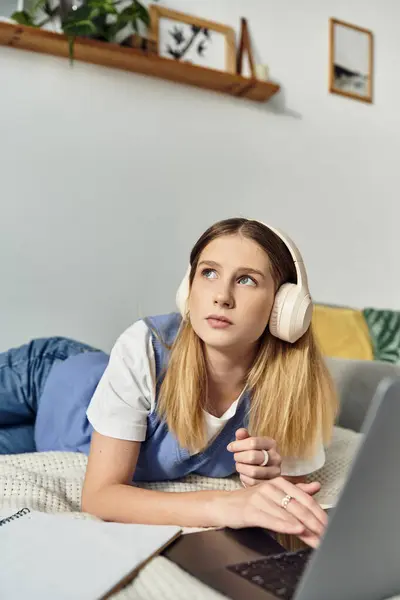 Teenage girl relaxes in her stylish room, immersed in music while using her laptop. — Stock Photo
