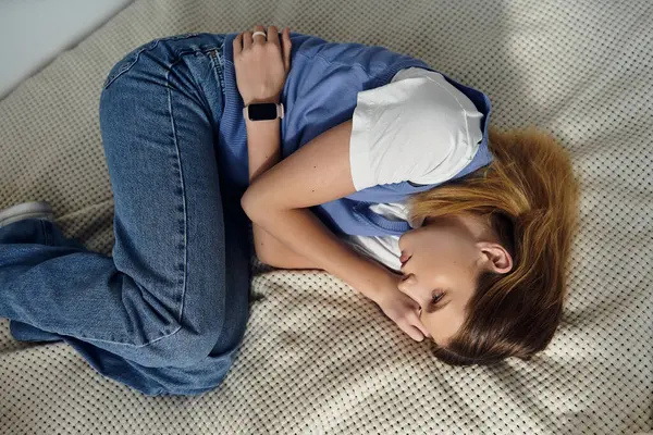 A pretty teenage girl curls up in her cozy room, enjoying a peaceful moment at home. — Stock Photo