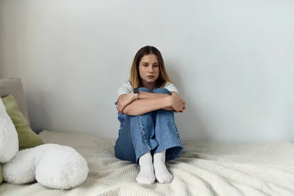 A teenage girl sits on her bed, lost in thought in her modern, personal space. — Stock Photo